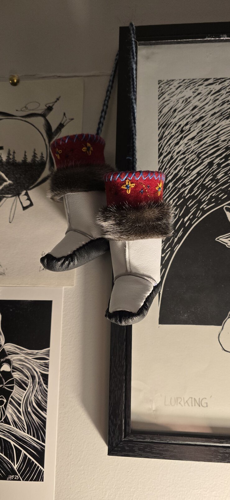 Miniature kamiik — small hand-sewn boots with red embroidered felt cuffs and fur trim